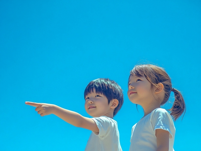 青空の下うれしそうに遠くを指さす二人の子ども