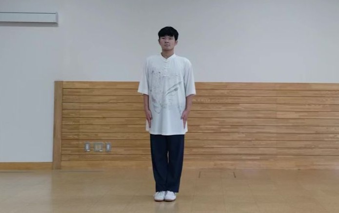 白い服のコーチが気をつけして入門長拳の演武に備えている。