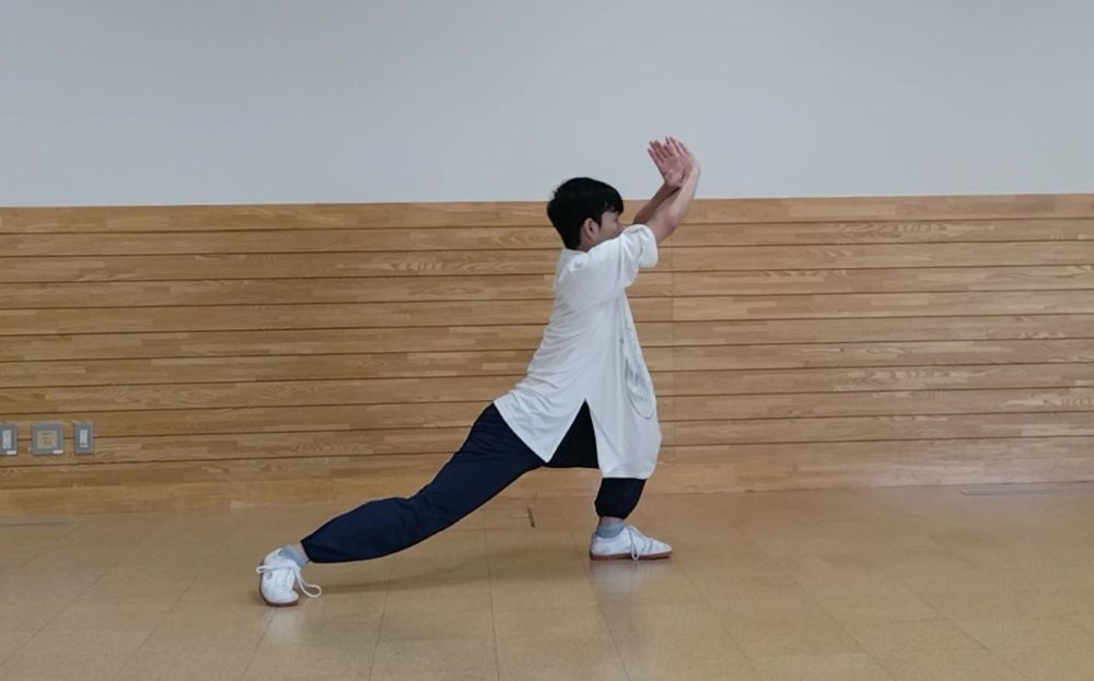 両手をクロスして額の前へ掲げている。