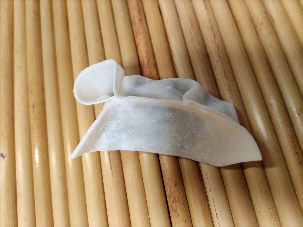 餃子の包みかけ。手前側がくっついて、カーブしている。